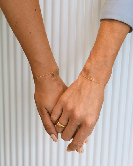 Zwei Frauen halten Hände, ihre Handgelenke mit Eternal Bracelets geschmückt, als Zeichen von Freundschaft und Nähe.